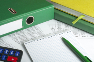 Calculator, accounting books and pen on background of financial document. Financial and budget concept.